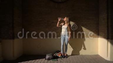 全长视野少女穿着休闲服饮水从瓶身背景的砖墙。